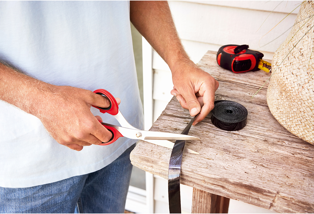 Απεικονίζεται άτομο να κόβει την κολλητική ταινία με ψαλίδι.